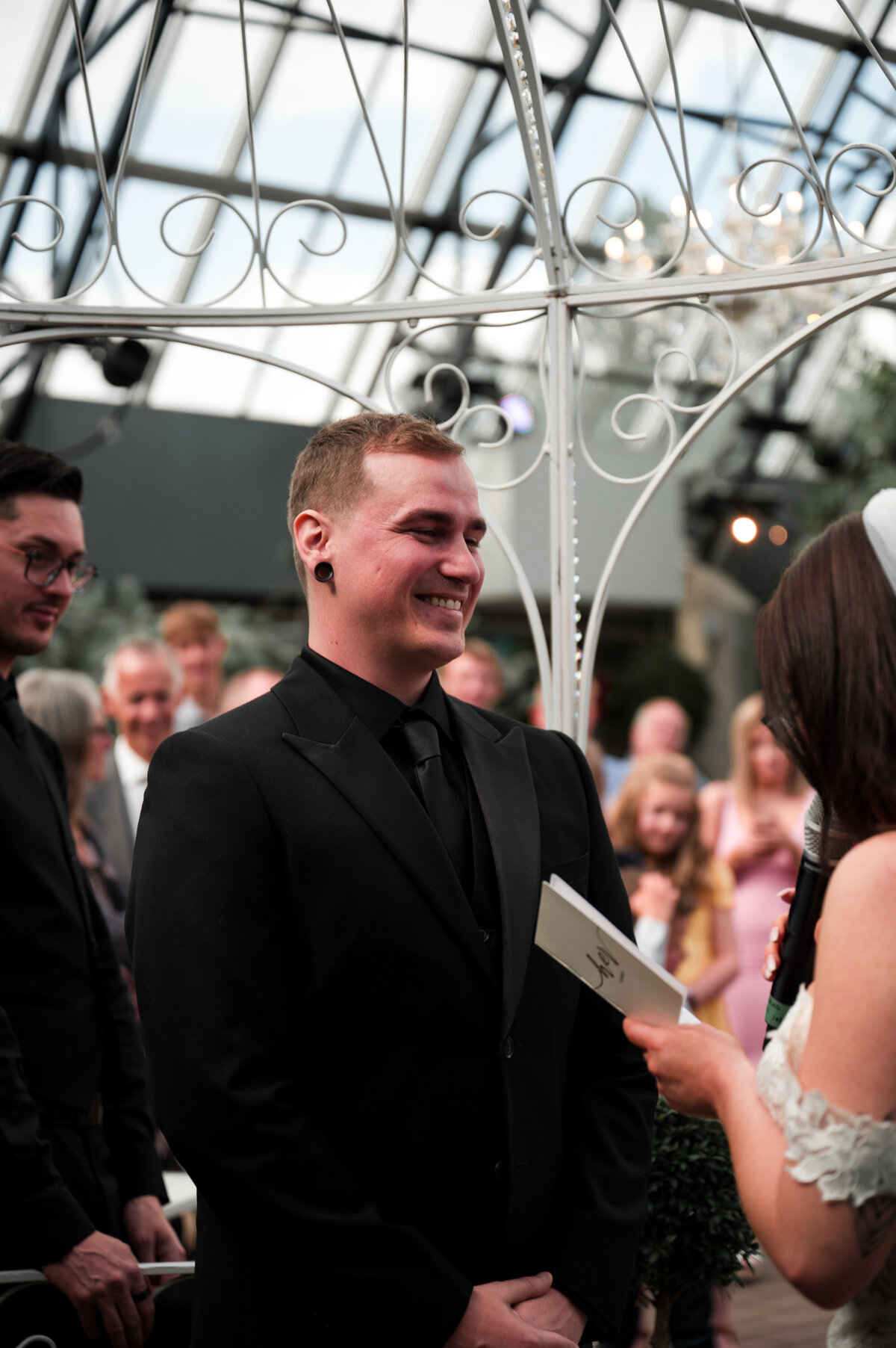 groom smiling at his bride as she reads her vows to him