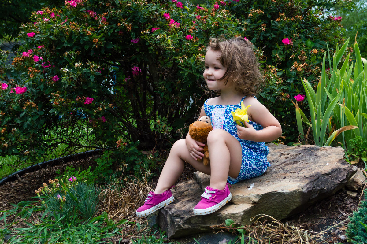 A young girl sits on a rock during her photo session.