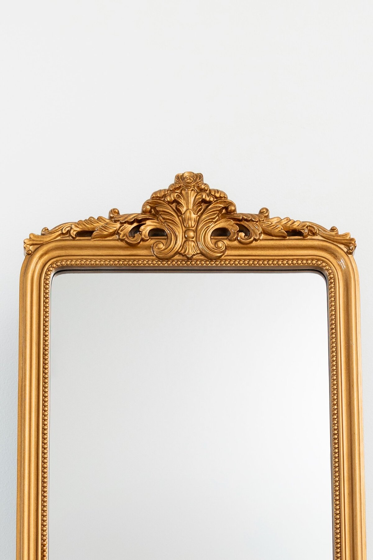 Medium vertical mirror with ornate ornament on top 