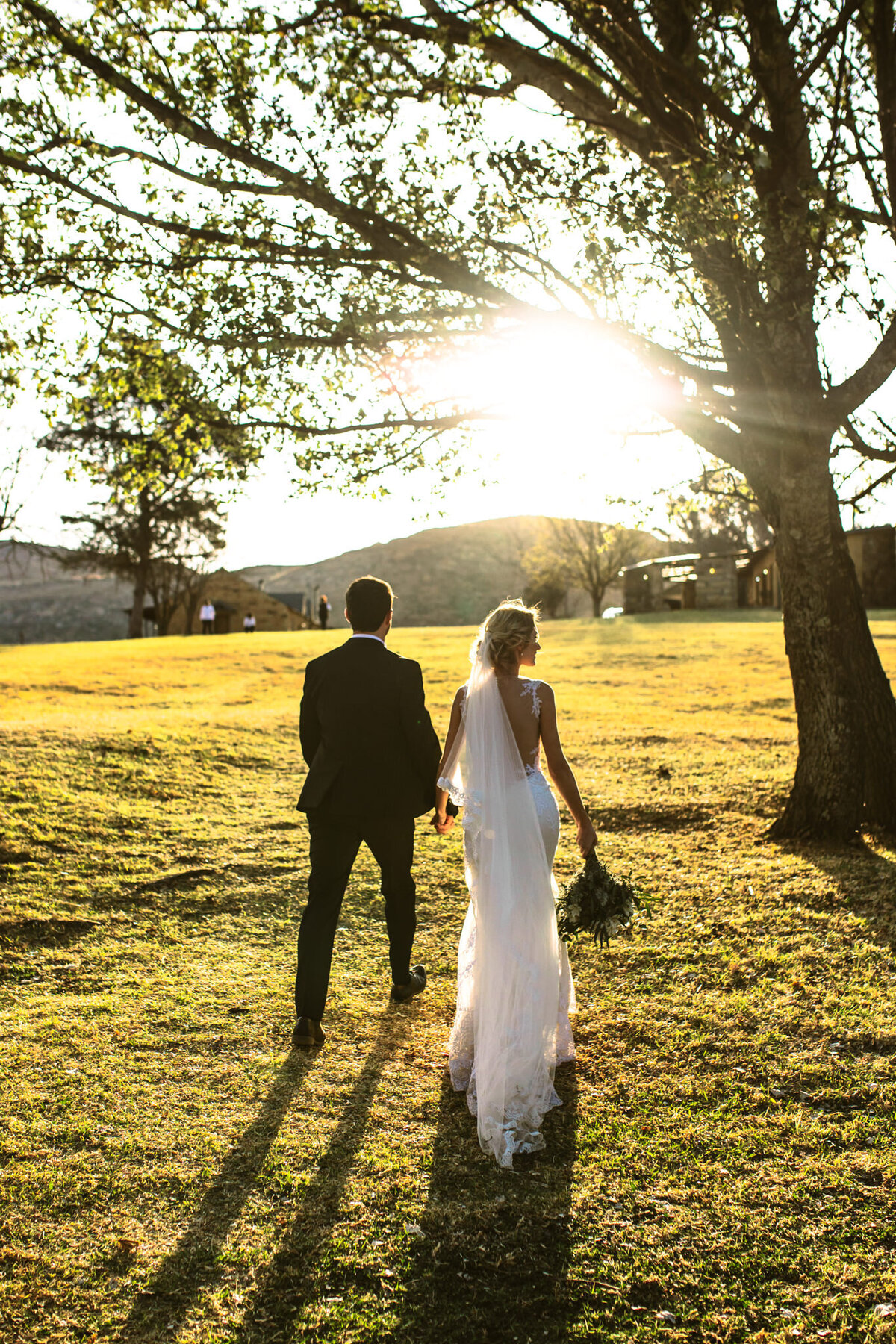 Joyful candid moment of the bridal couple walking into the sunshine, photographed by Bendigo Wedding Photographer. 