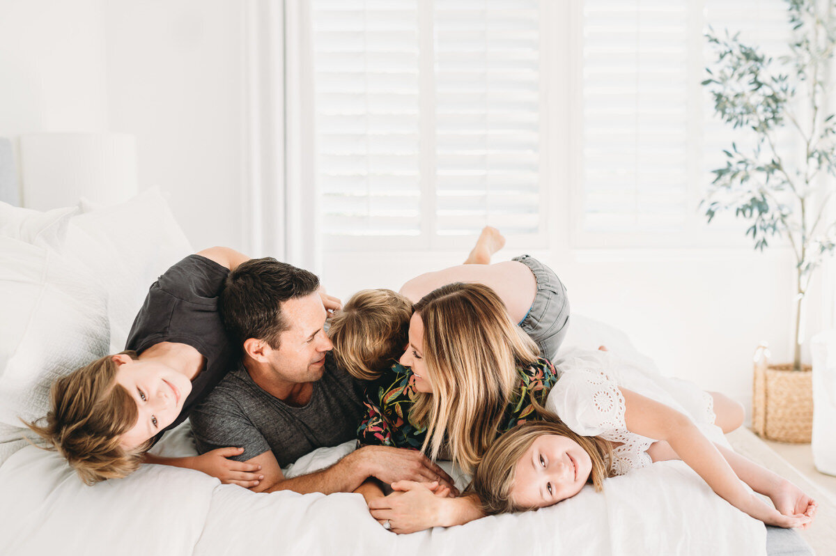 family snuggling on bed