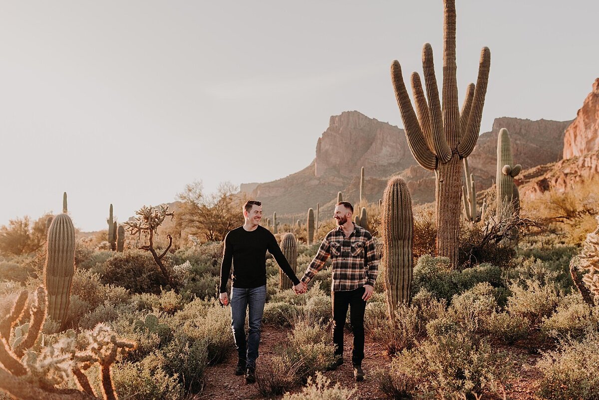 Two men stand side by side holding hands in the desert