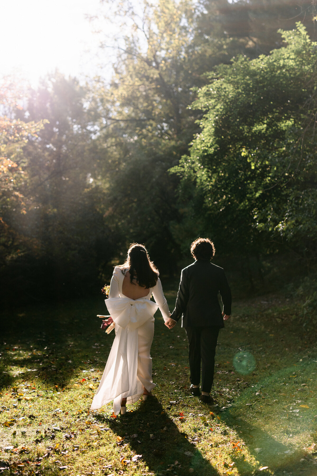 Bride and groom holding hands walking away from camera