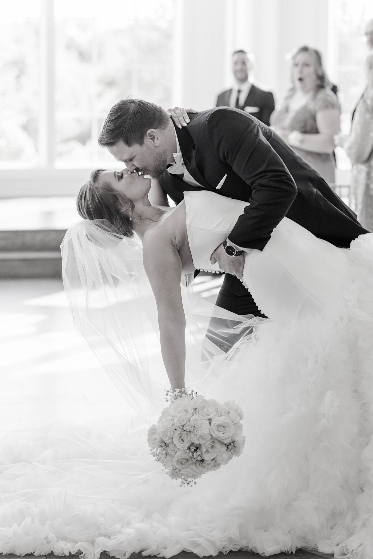 bride-and-groom-dip-for-a-kiss-in-the-chapel-aisle-in-black-and-white