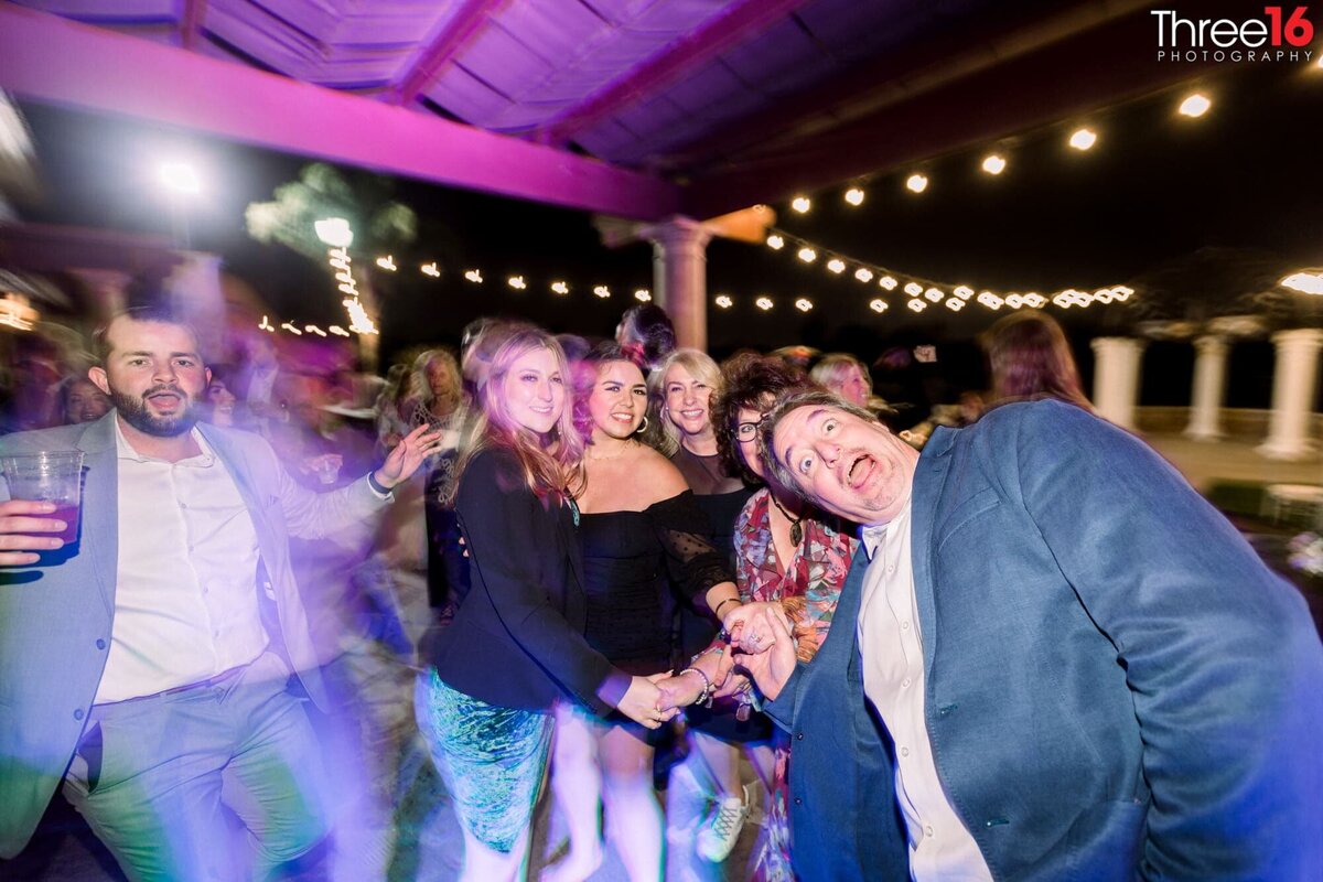 Wedding guests act silly while on the dance floor for the photographer