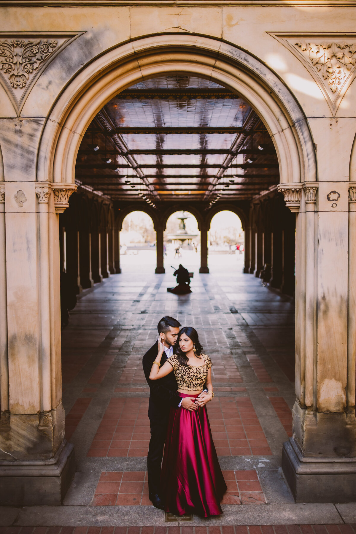 A couple sharing a moment during their engagement session in traditional indian clothes in front of the bethesda terrace at central park nyc