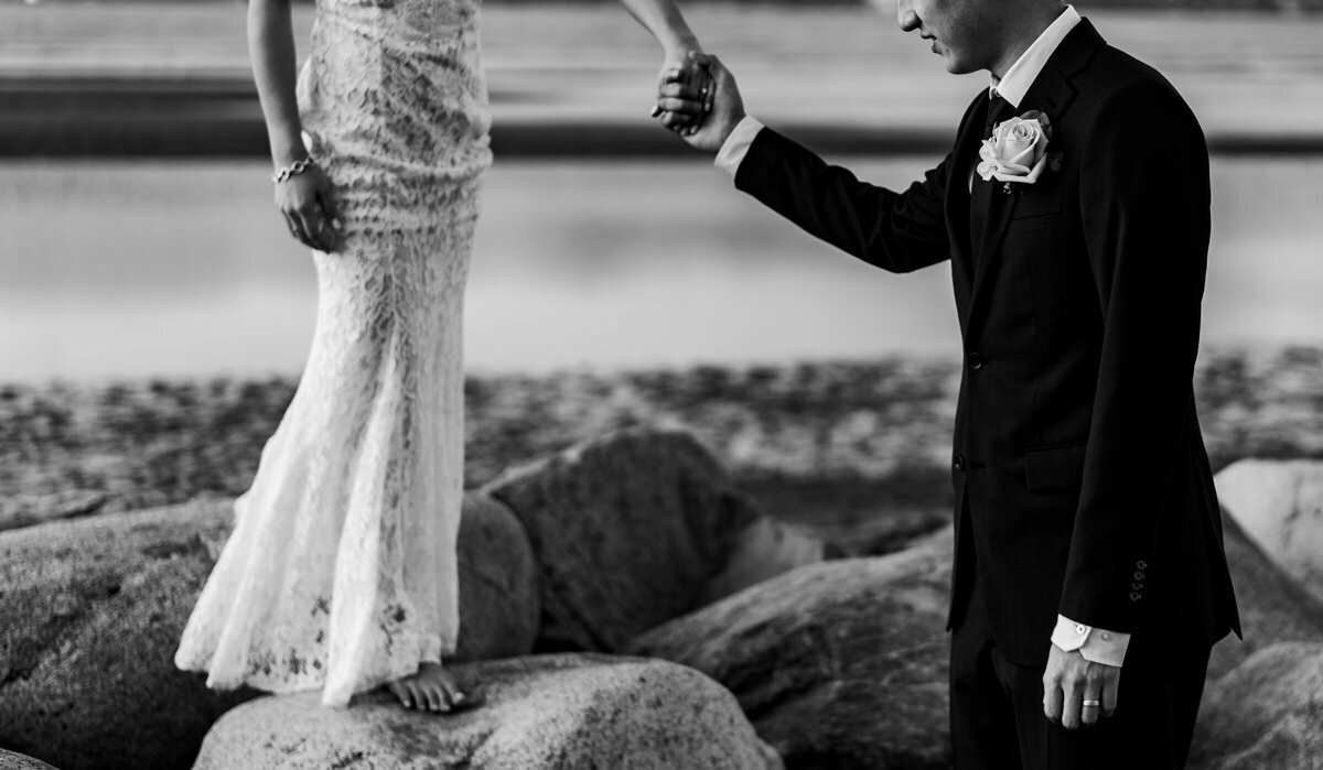 groom helping bride down rocks
