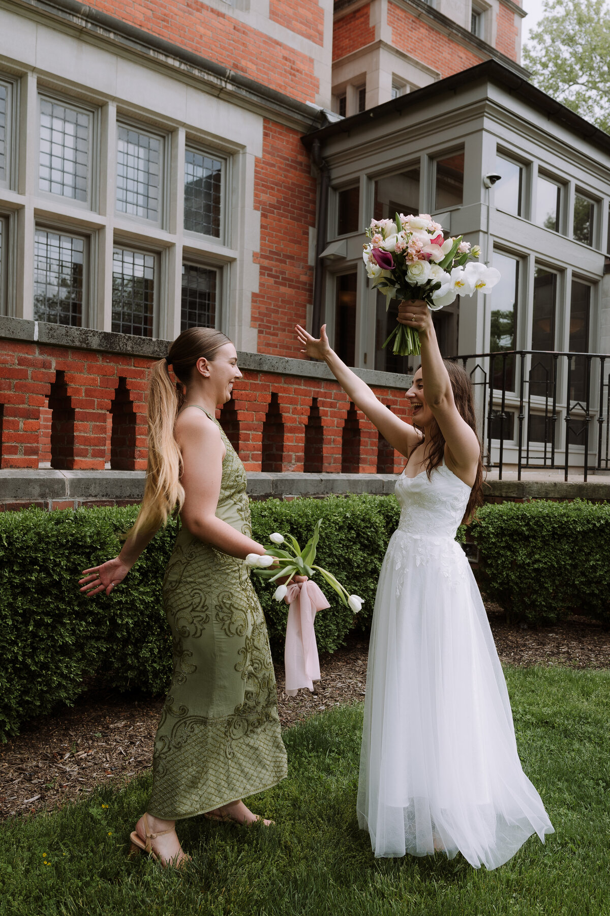 bride celebrating with bridesmaid in green dress, outdoors