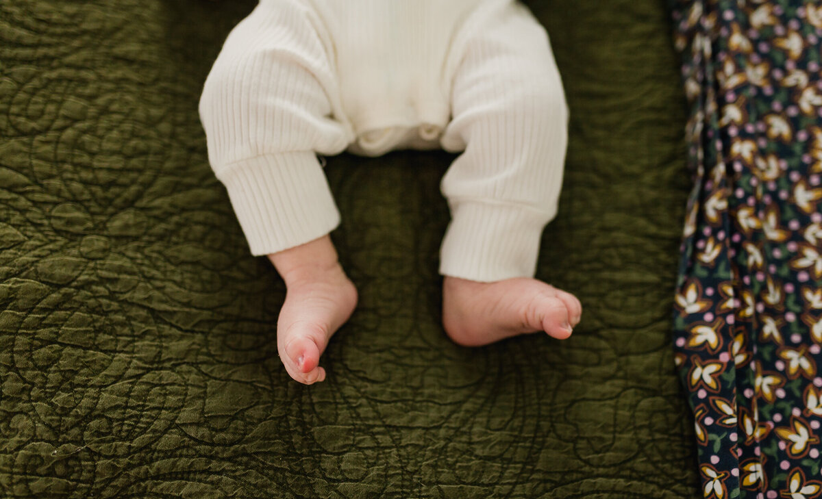 Newborn baby sleeping in bed, feet and toes showing.