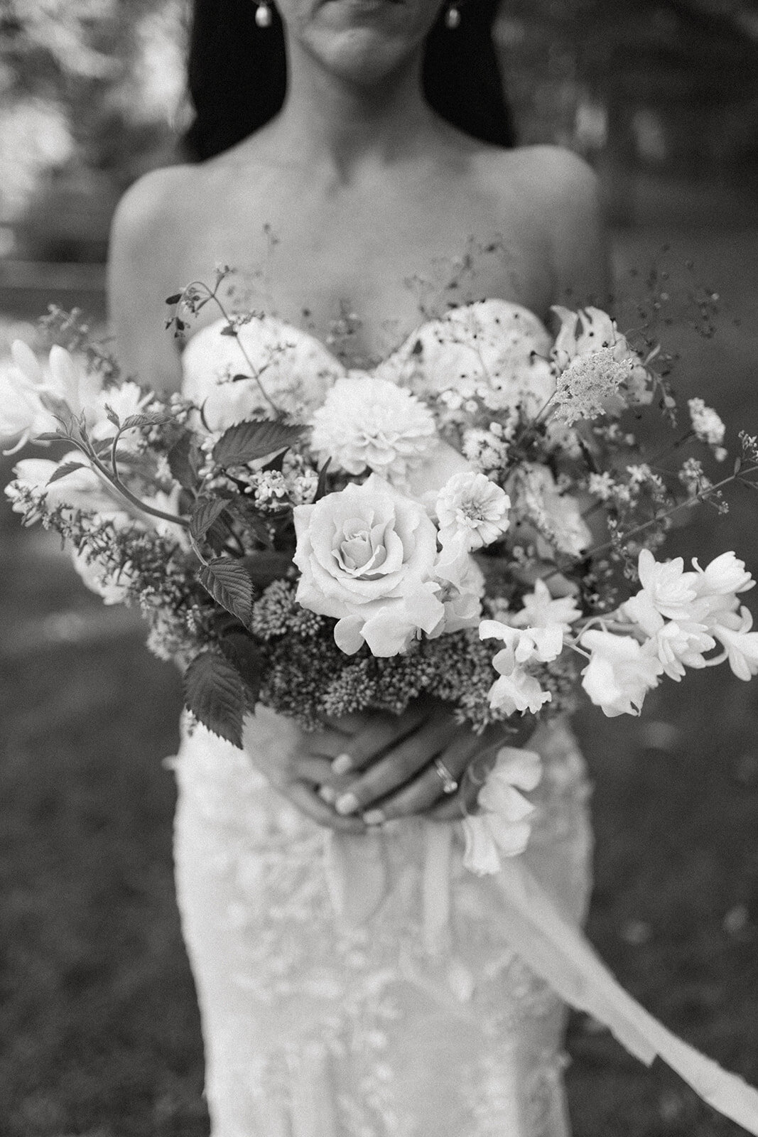 Bride holding a romantic white and blush bouquet with seasonal florals at Glasshouse Community wedding in Ottawa County.