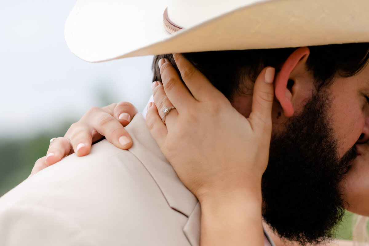 Little Rock wedding photographer captures detail shot of brides ring as she holds the bakc of her grooms neck and kisses him