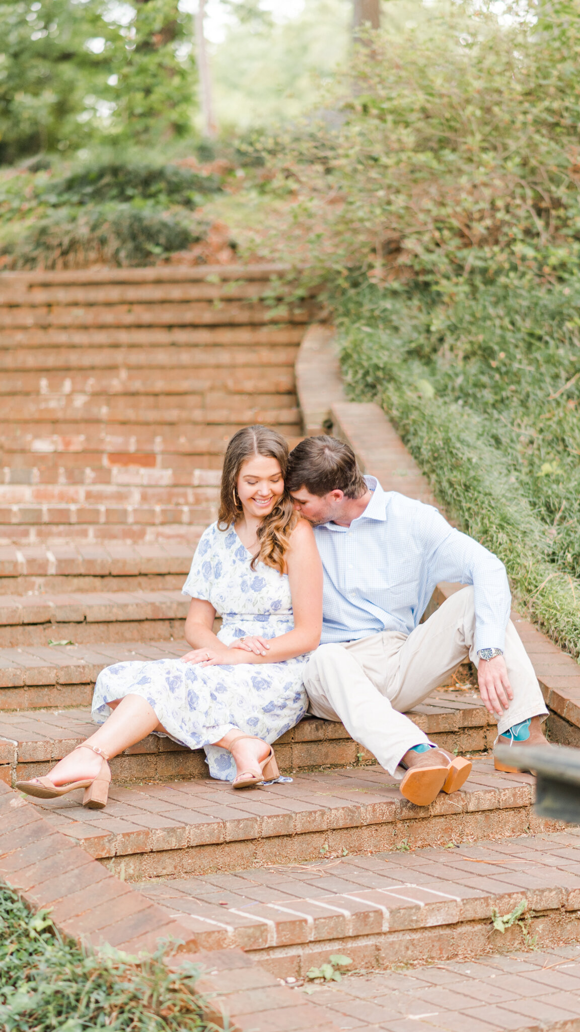 couple sitting on stairs smiling in wilmington, nc