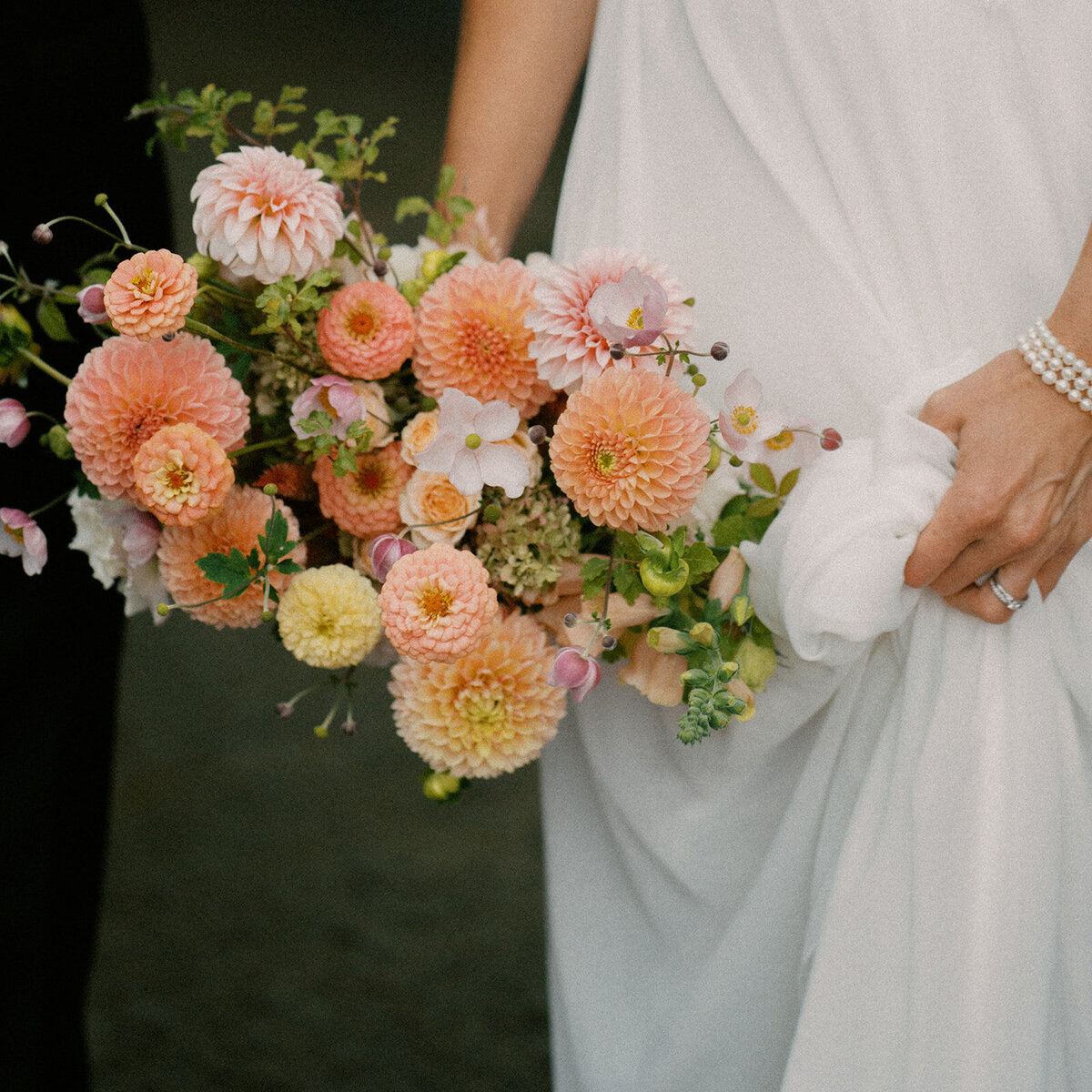 A closeup of a bridal bouquet of bright, pink and peach dahlias at a Montreal wedding.