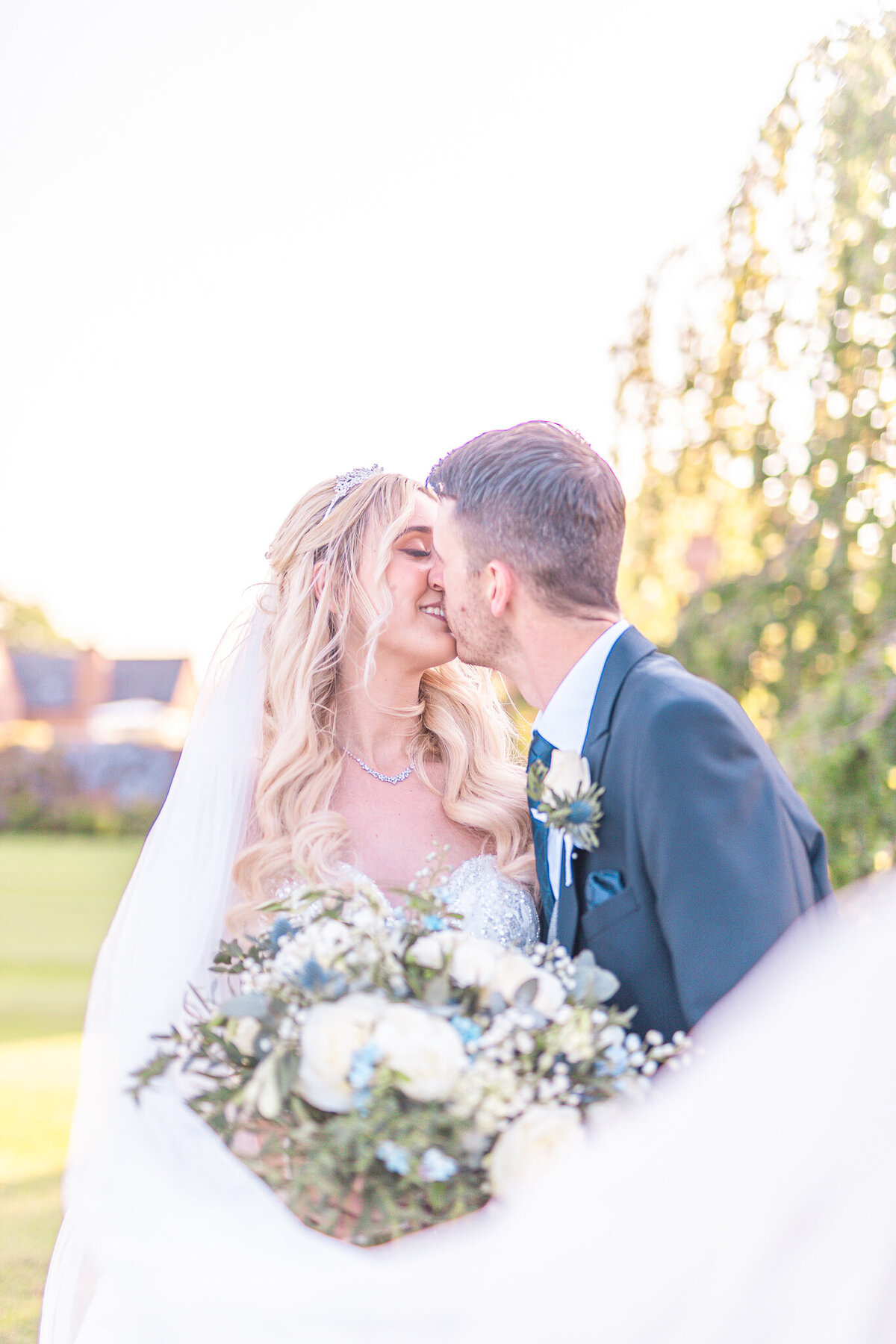 Bride and groom kissing with veil in front of bouquet at Merrydale Manor Cheshire Wedding