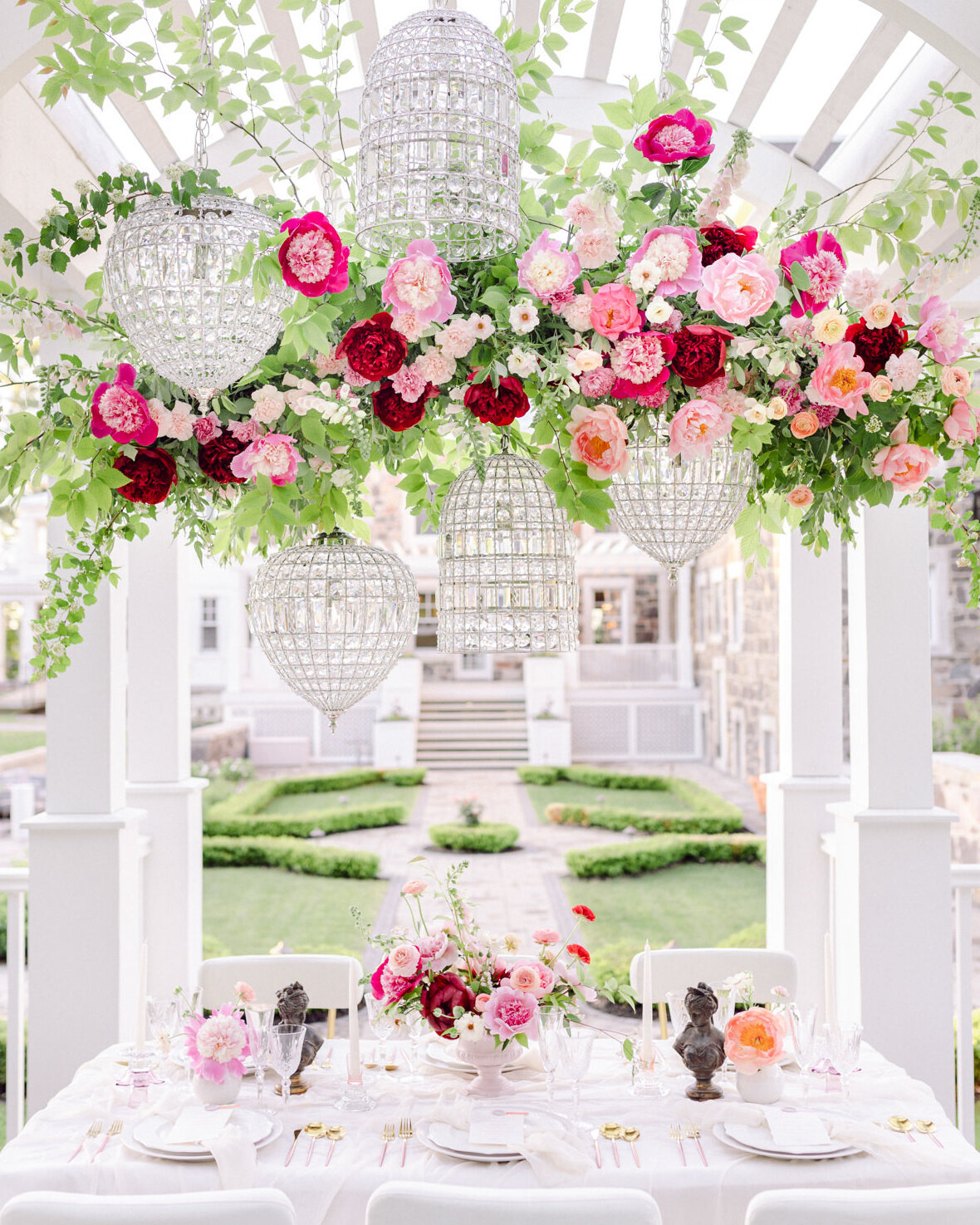 A large, lush arrangement of pink flowers is suspended above a table at Stonehaven Manor.