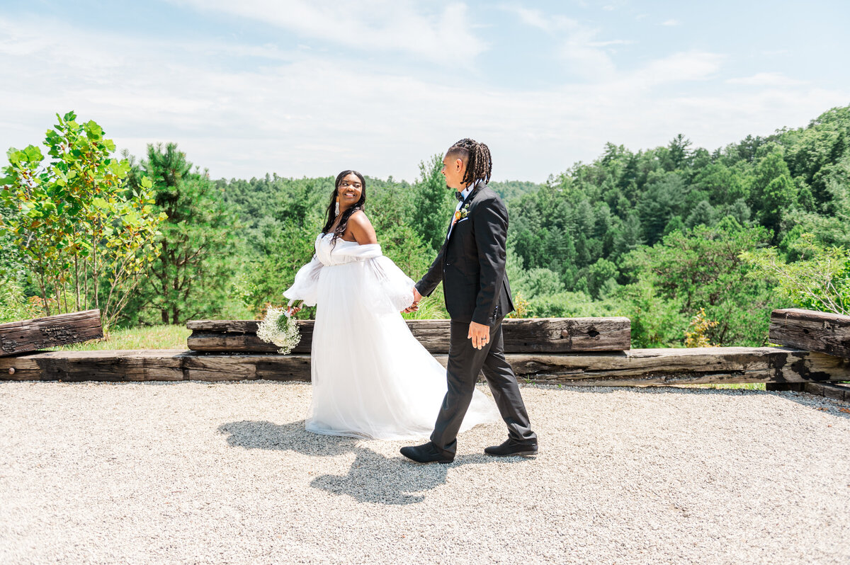 Bride leading groom while holding flowers among a stunning backdrop at Clifton Resort