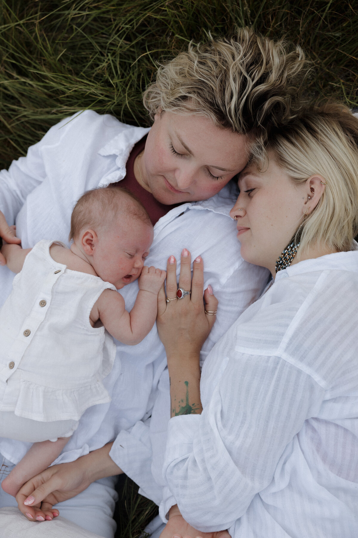 A tender moment of a couple and their newborn in an outdoor setting, embodying authentic and artistic wedding photography.