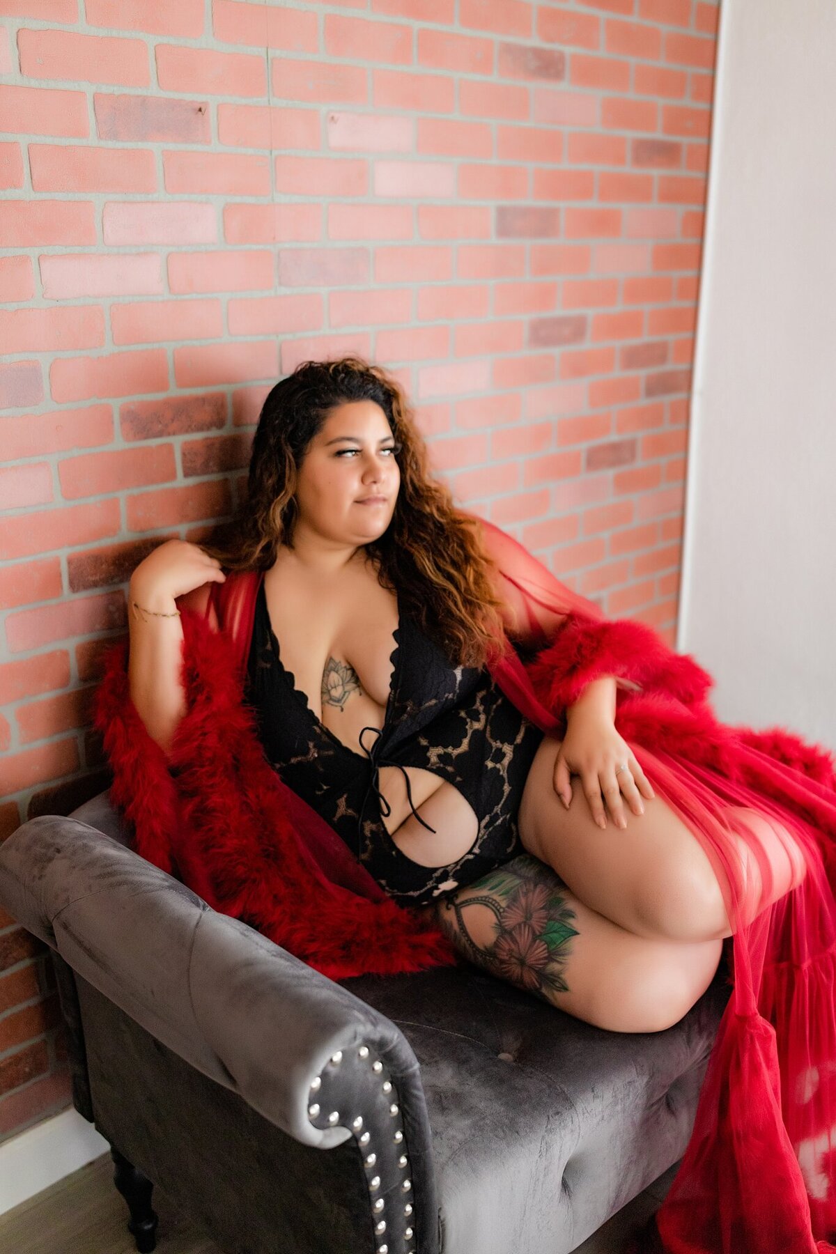 woman posing for boudoir photos on grey velvet lounge, photo by Love is Magic Photo