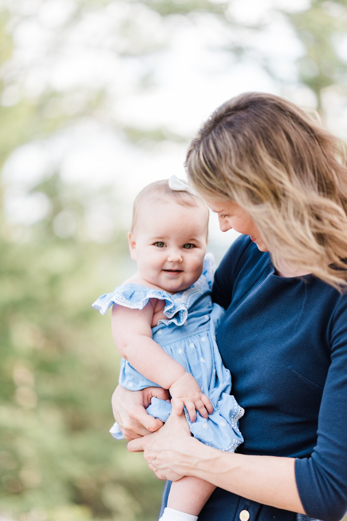 family outdoor photos with denver family photographers photographing mother holding baby daughter as she smiles at her in the woods