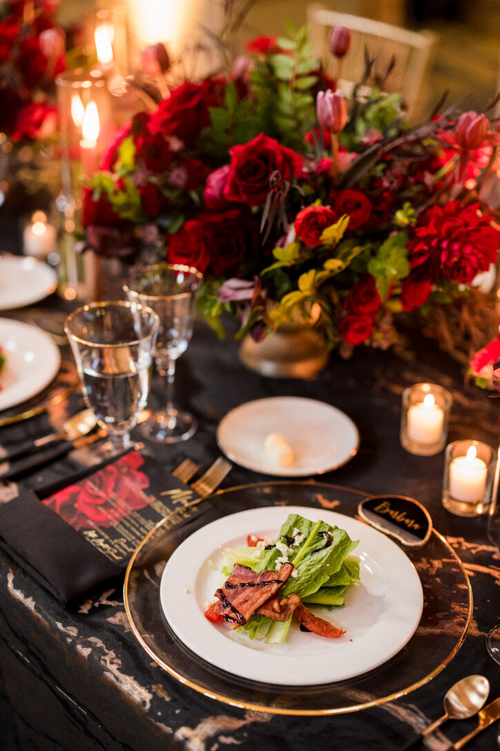 Gold charger, salad, gold accents, black linens, red flowers, gold footed dishes, menu,