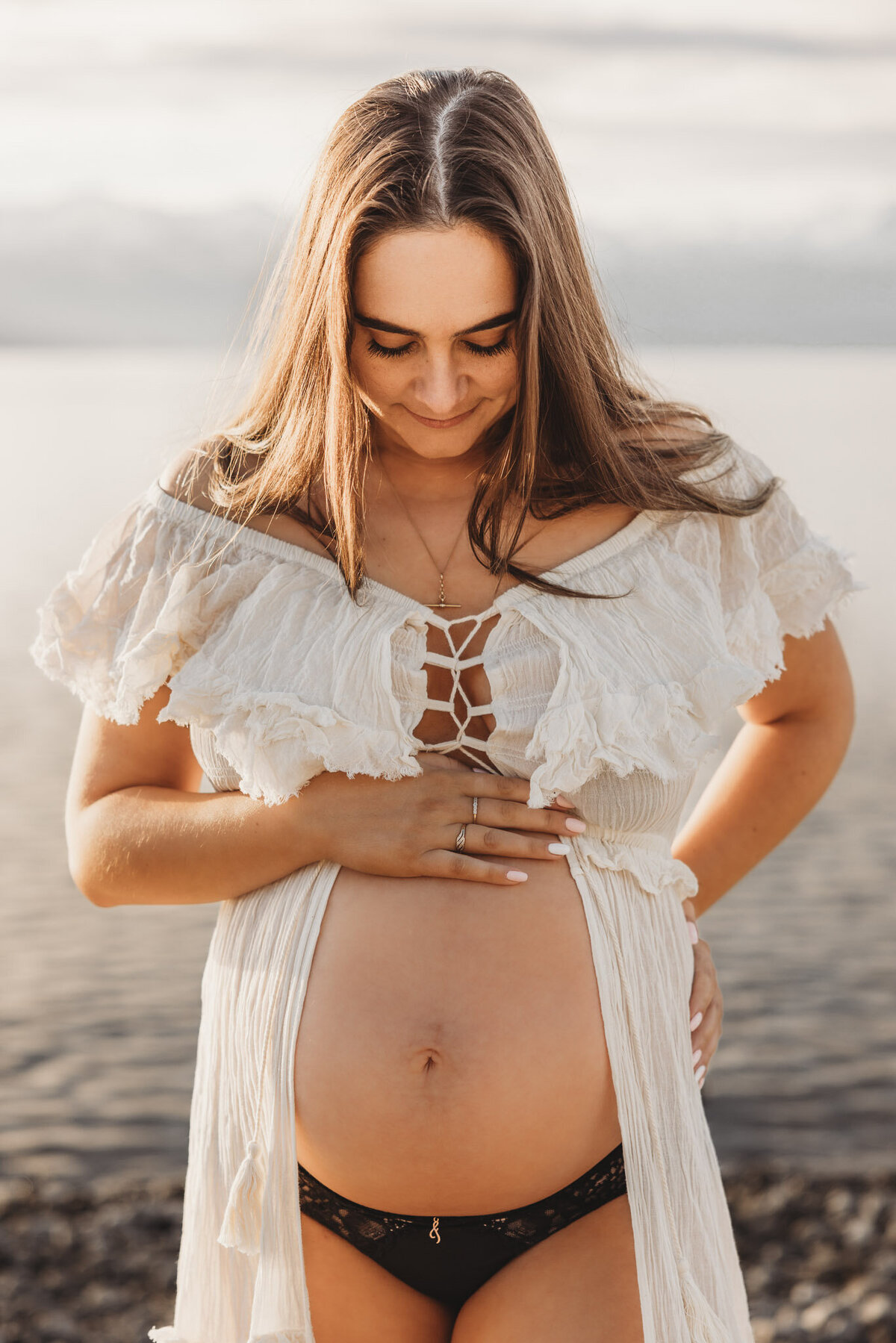 pregnant woman standing with hand on belly in wanaka during her maternity session