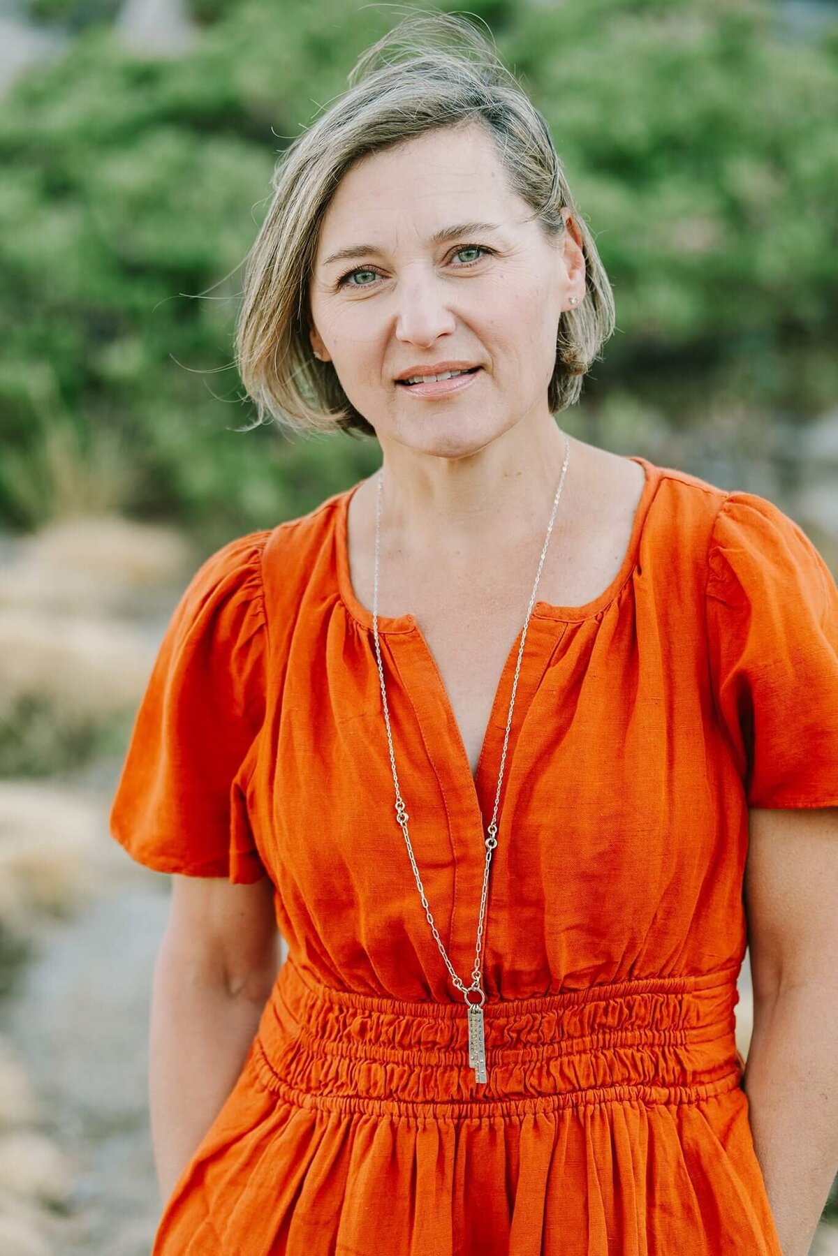 mother in burned orange dress facing camera on donner summit during a family session