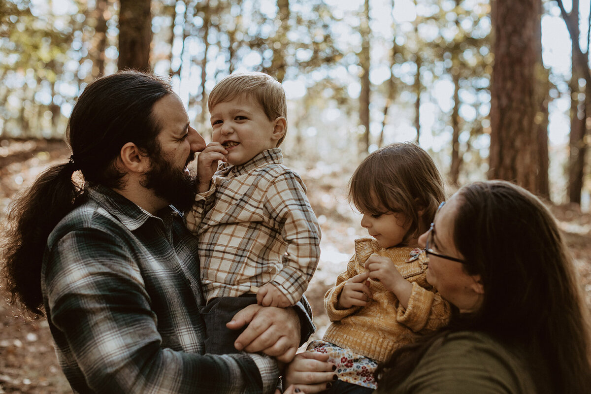 parents and twins laugh together in the forest