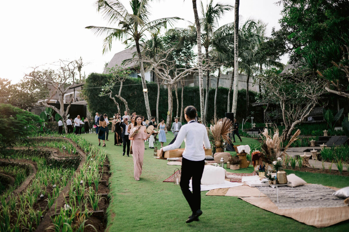 The wedding guests are walking towards the reception in a lovely garden in Khayangan Estate, Bali, Indonesia. Image by Jenny Fu Studio