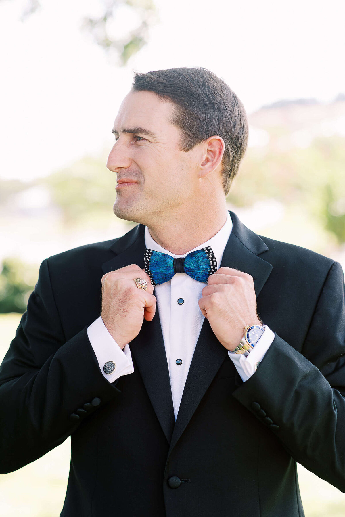 Classy groom wears blue and black bowtie and watch