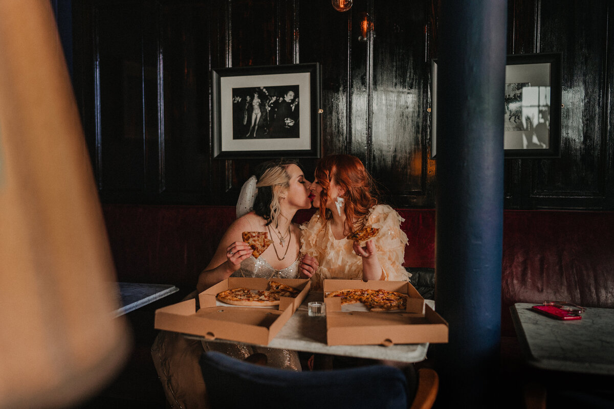 Intimate wedding photography of two brides kissing in a  citycafe