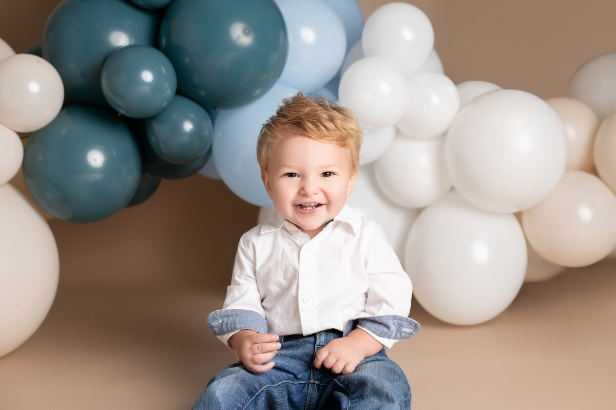 Easton James Cameron posing with white balloons in baby milestone session by Houston photographer