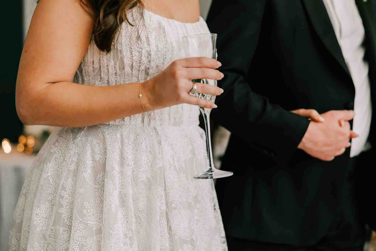 bride and groom hold hands while listening to speeches given at their wedding day.