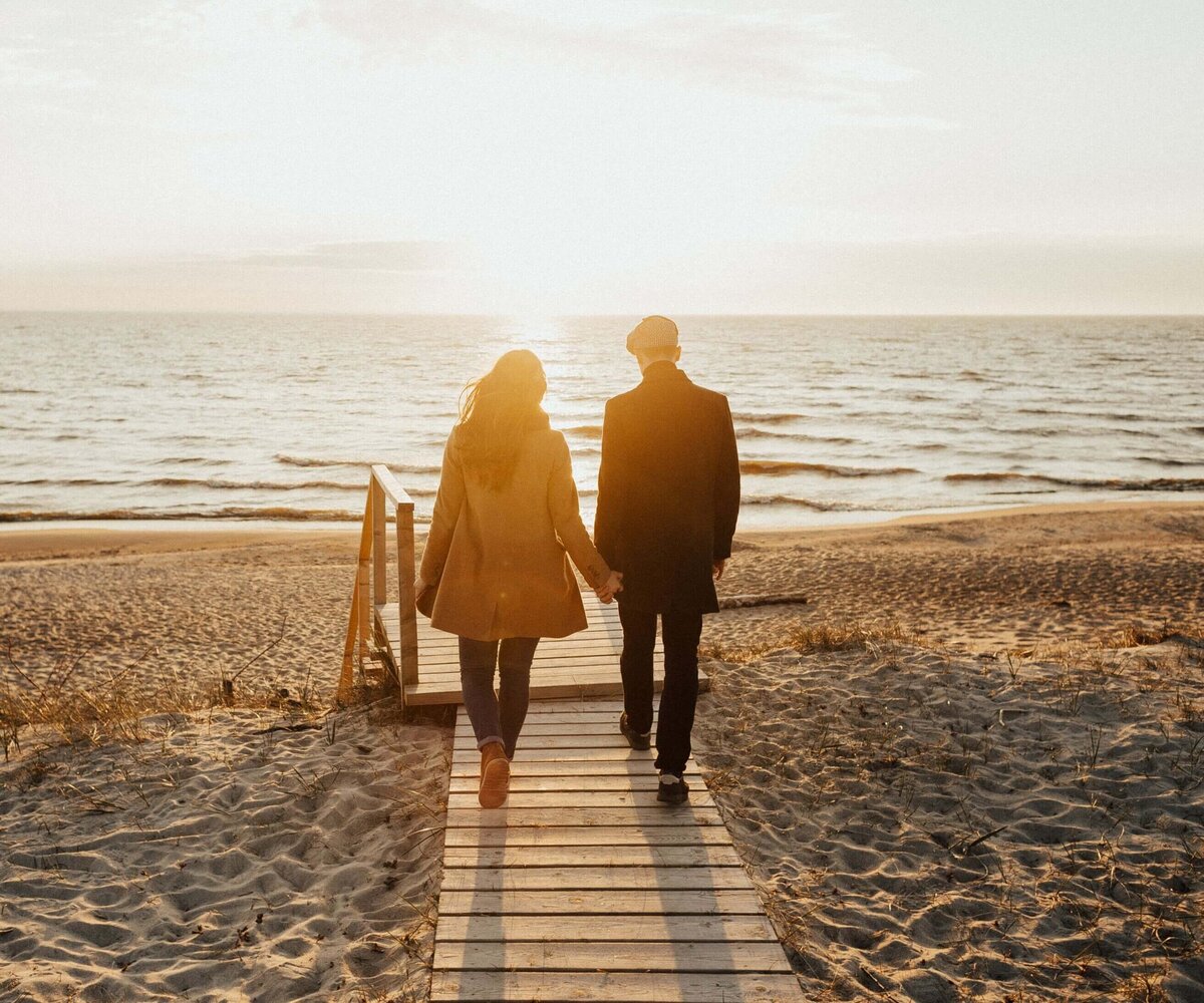 A Couple Walking on a Beach while Holding Hands