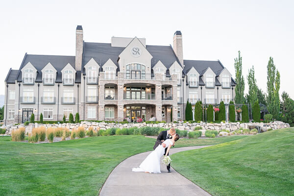 Salt Lake Photography of a bride and groom kissing in front of Sleepy Ridge Golf Course clubhouse at dusk.