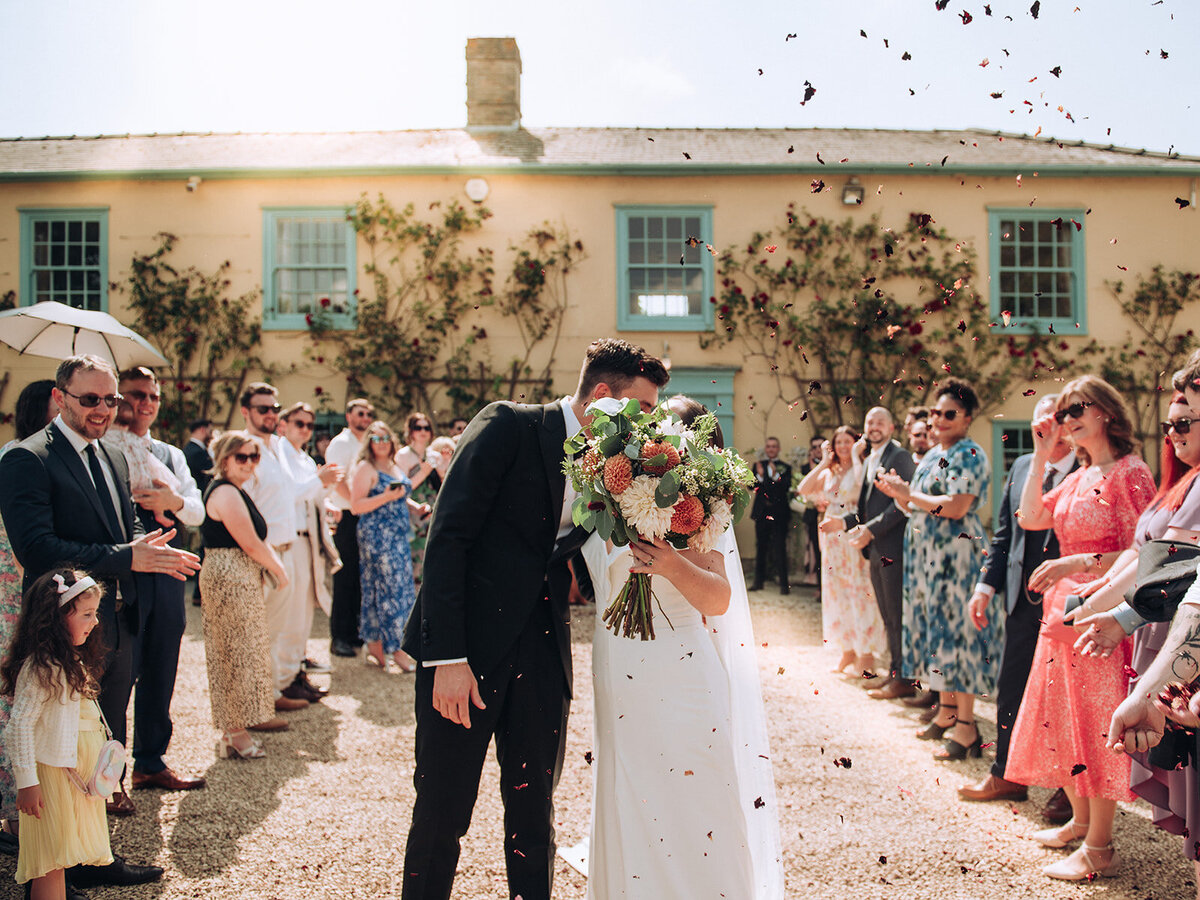 Confetti shot while couple are kissing at wedding at South Farm in Cambridge