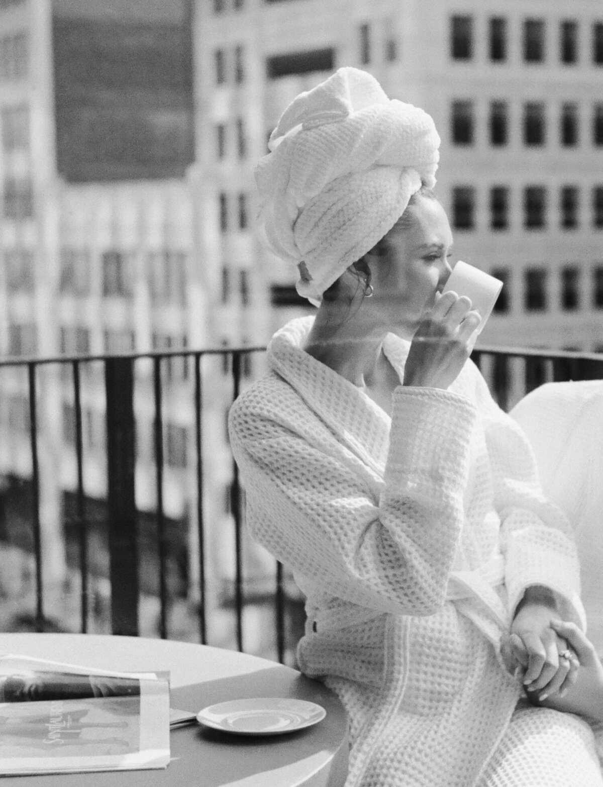 woman in bathrobe and hair towel sips coffee for brunch on Shinola Hotel balcony in Detroit