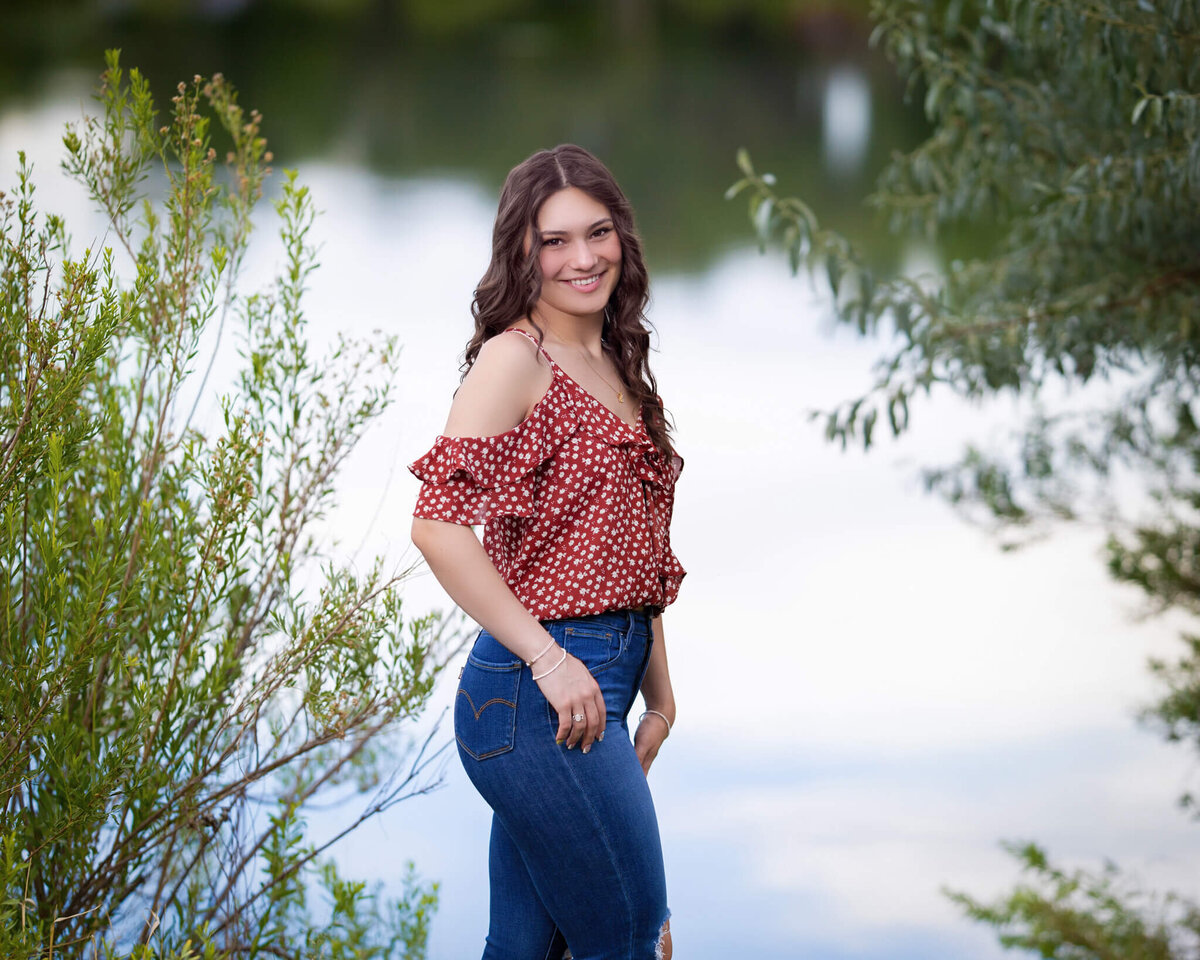 high school senior girl standing near reflective pond