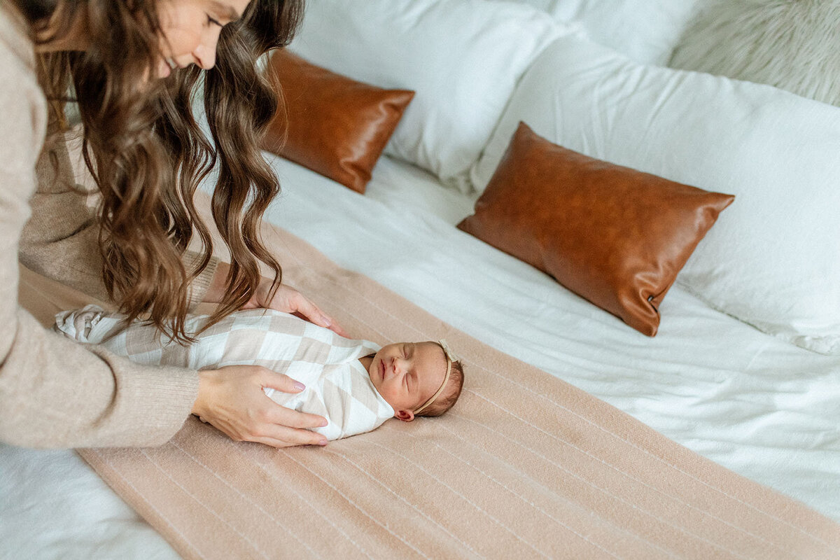 Mother bonding with baby on bed - Sara James documents maternal connection and early motherhood moments during tender newborn sessions in intimate San Antonio Texas home environments