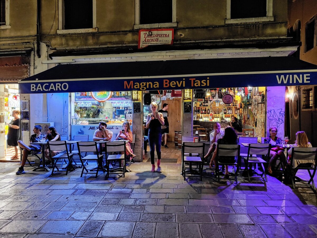 Tourist on phone in front of Venice bacaro Magna Bevi Tasi in Castello sestiere. 