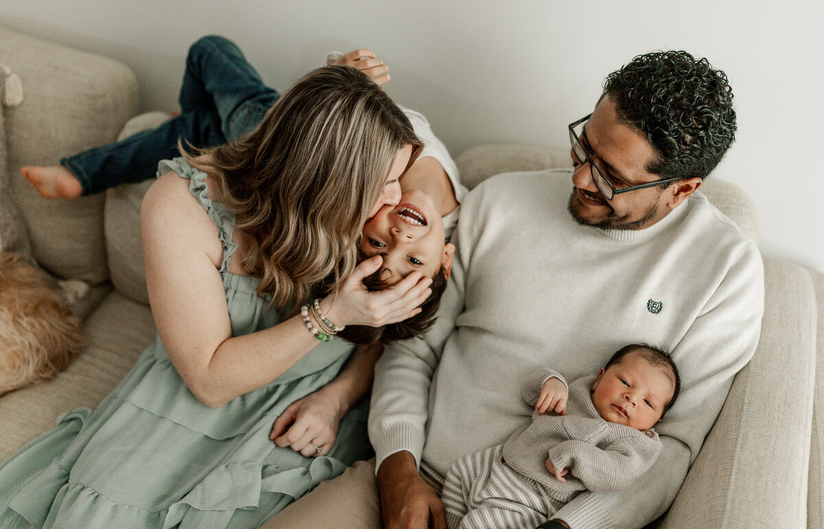 Mom kissing funny older brother during in home newborn session