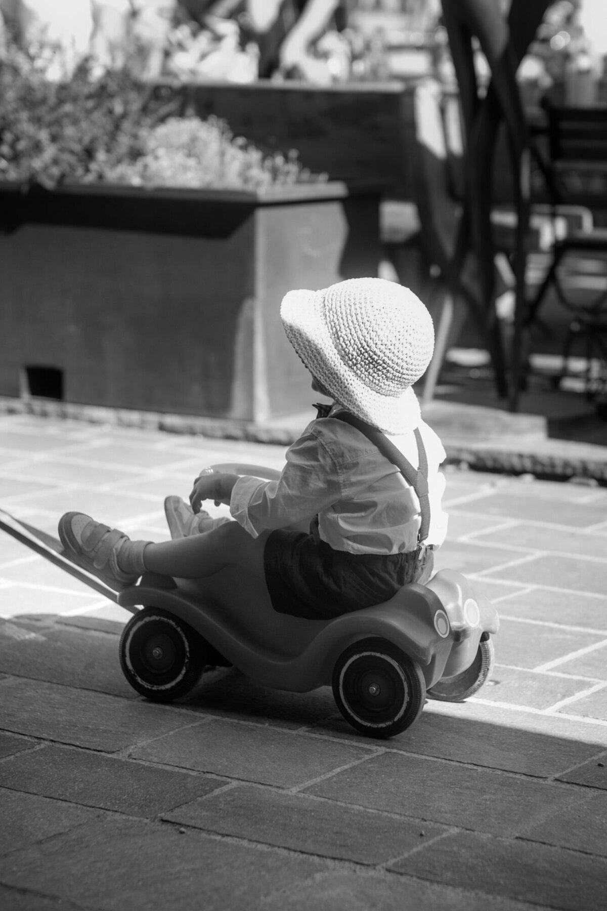 Ein kleines Kind lässt sich auf einem Bobby Car sitzend über einen Weg ziehen.