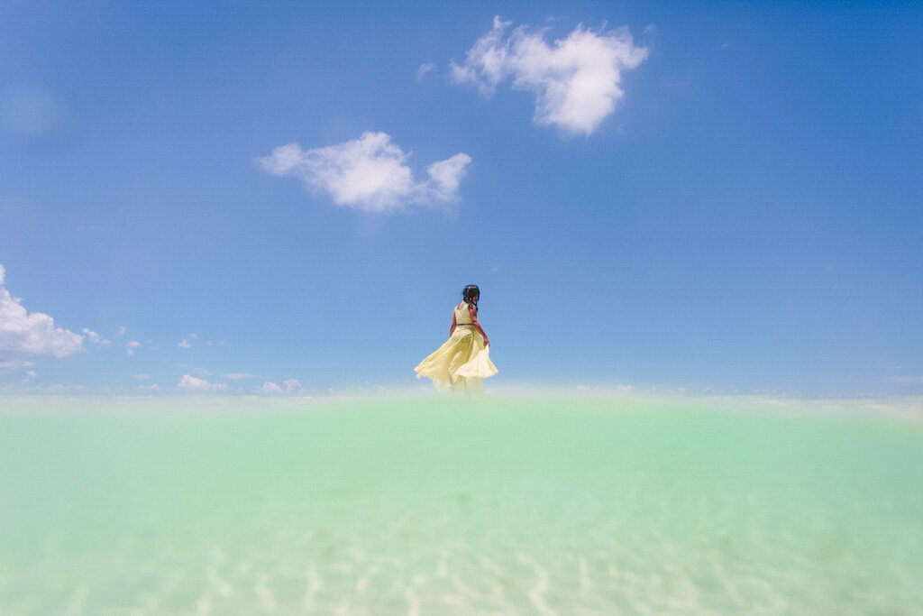 girl in yellow dress running on a sandbar