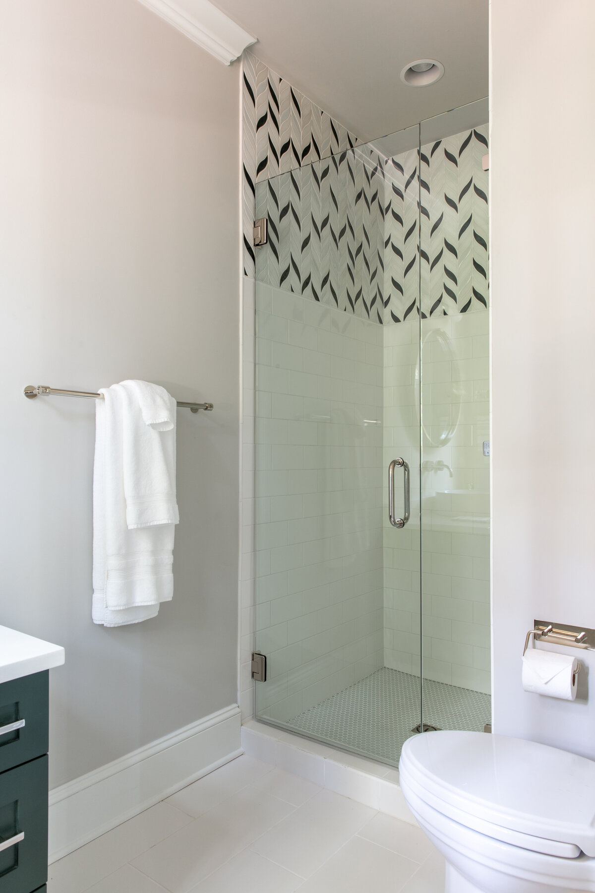 Modern bathroom in Kiawah Island, SC, featuring a glass shower with geometric tile accents and gold fixtures.