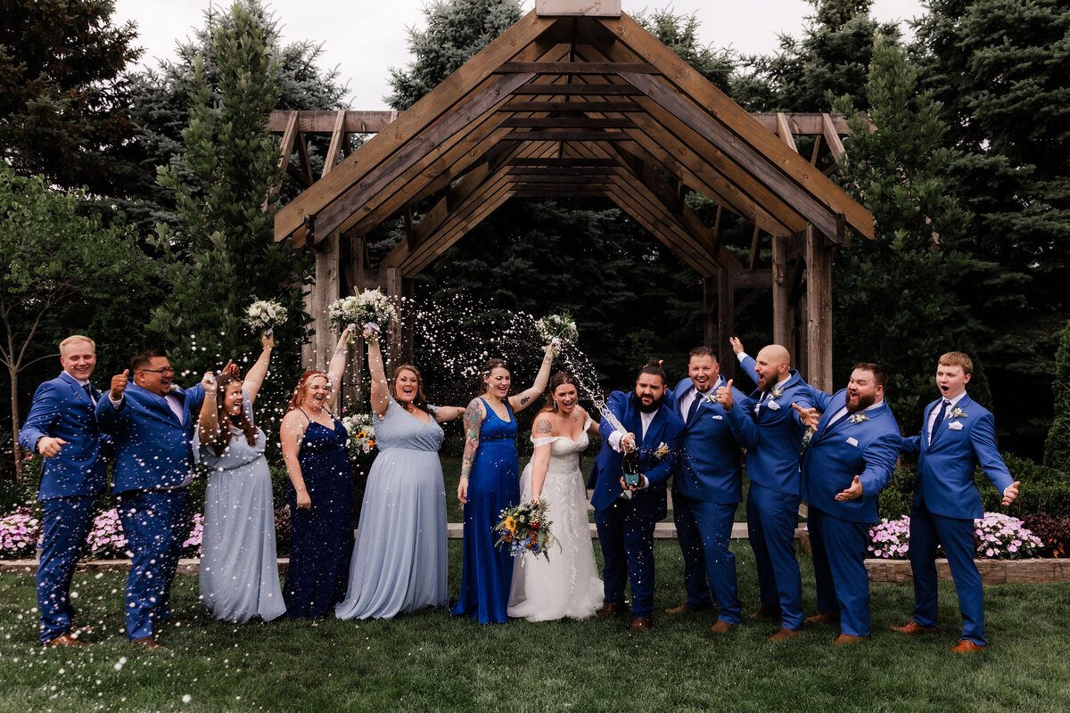 A wedding party pops champagne for a fun photo.