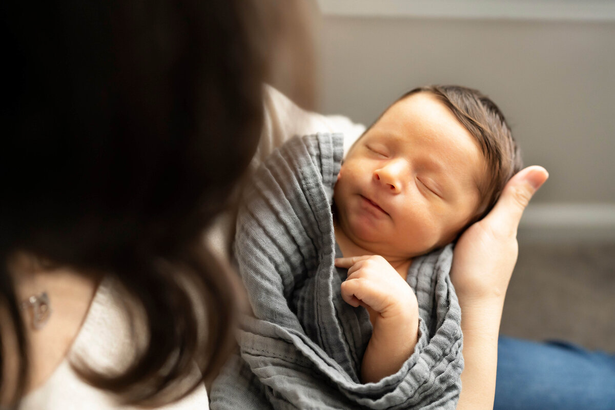 Newborn boy with brown hair in mother's arms