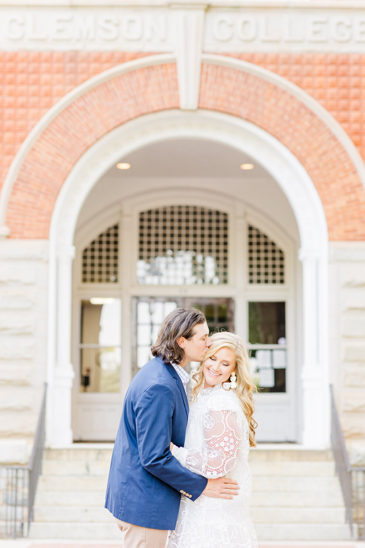 engaged couple kissing in front of a building at Clemson