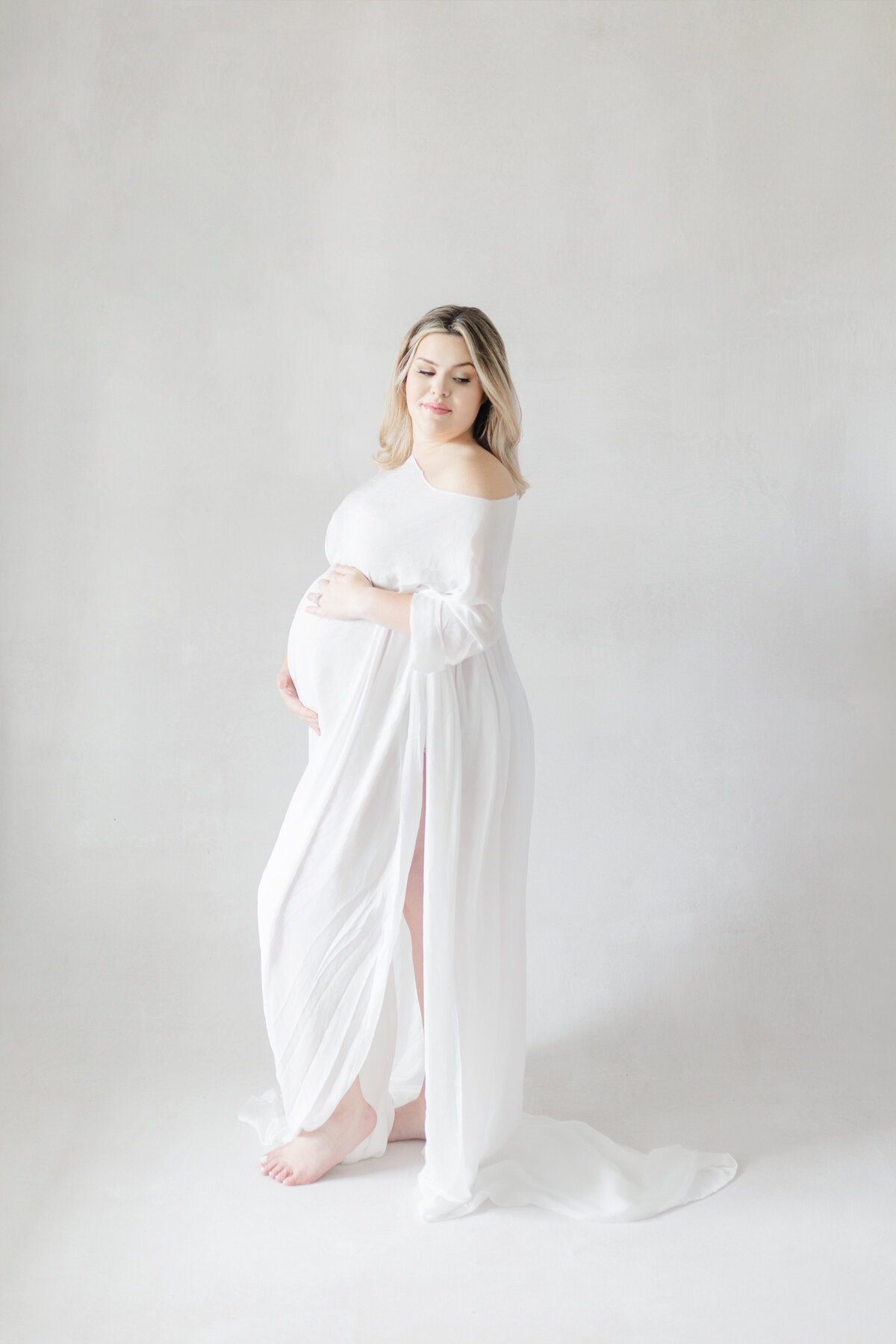 Sophisticated Tampa maternity portrait of mom-to-be in elegant gown on canvas backdrop