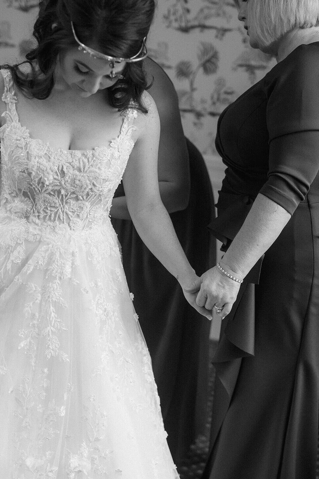 Bride holding her mothers hand before her wedding