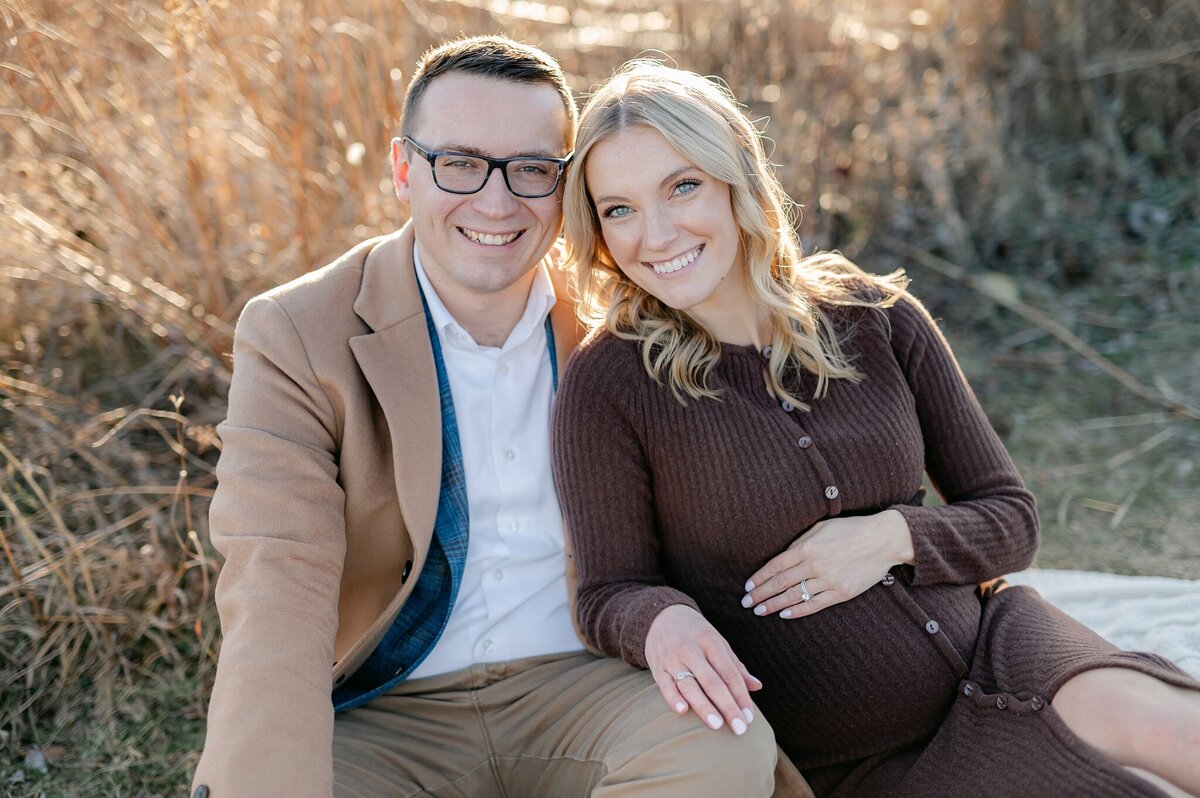 Two parents-to-be smiling at the camera for a portrait taken by Abby Park Photography