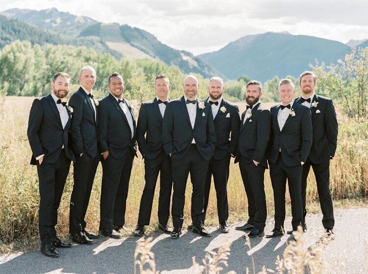 Groom and groomsmen in black at an outdoor wedding venue